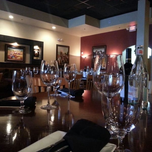 Elegant dining room at El Chaman Peruvian Cuisine with set tables, wine glasses, and Peruvian art.