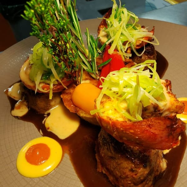 Peruvian dish with meat, shrimp, vegetables, and sauces, garnished with herbs on a plate.
